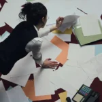 Mujer trabajando en suelo sobre varios documentos dispersos y desordenados