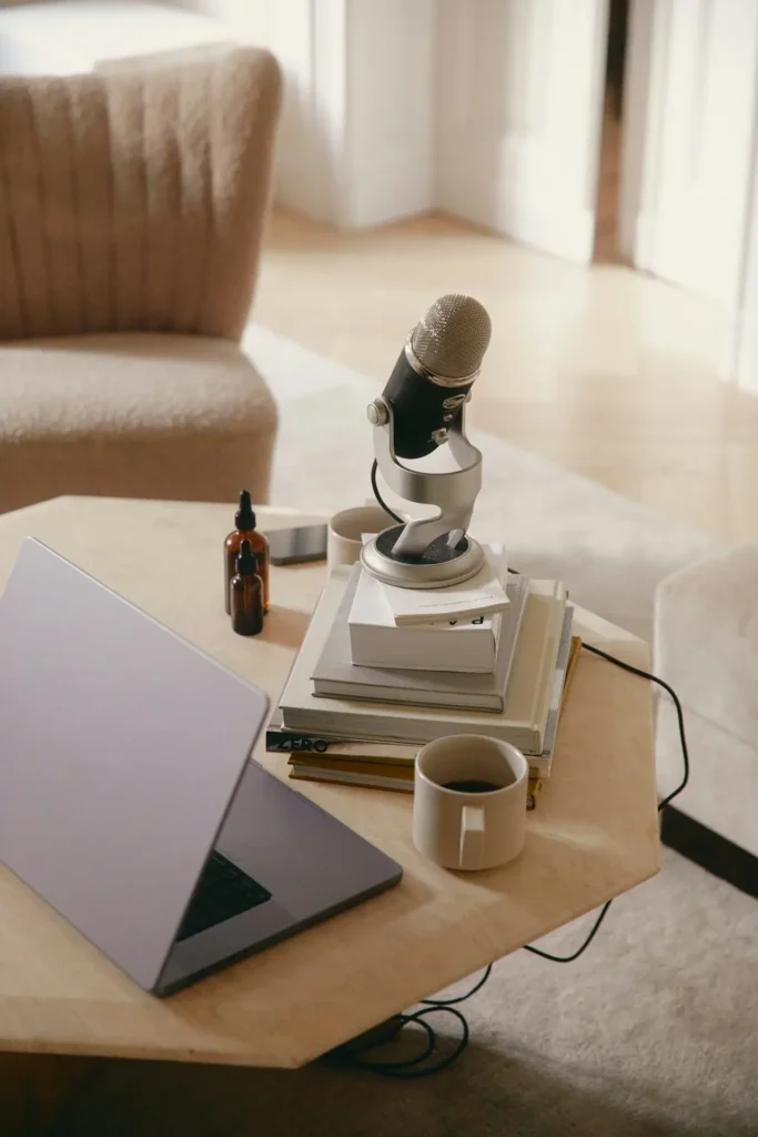 Mesa de trabajo con un prtatil, libros y micrófono